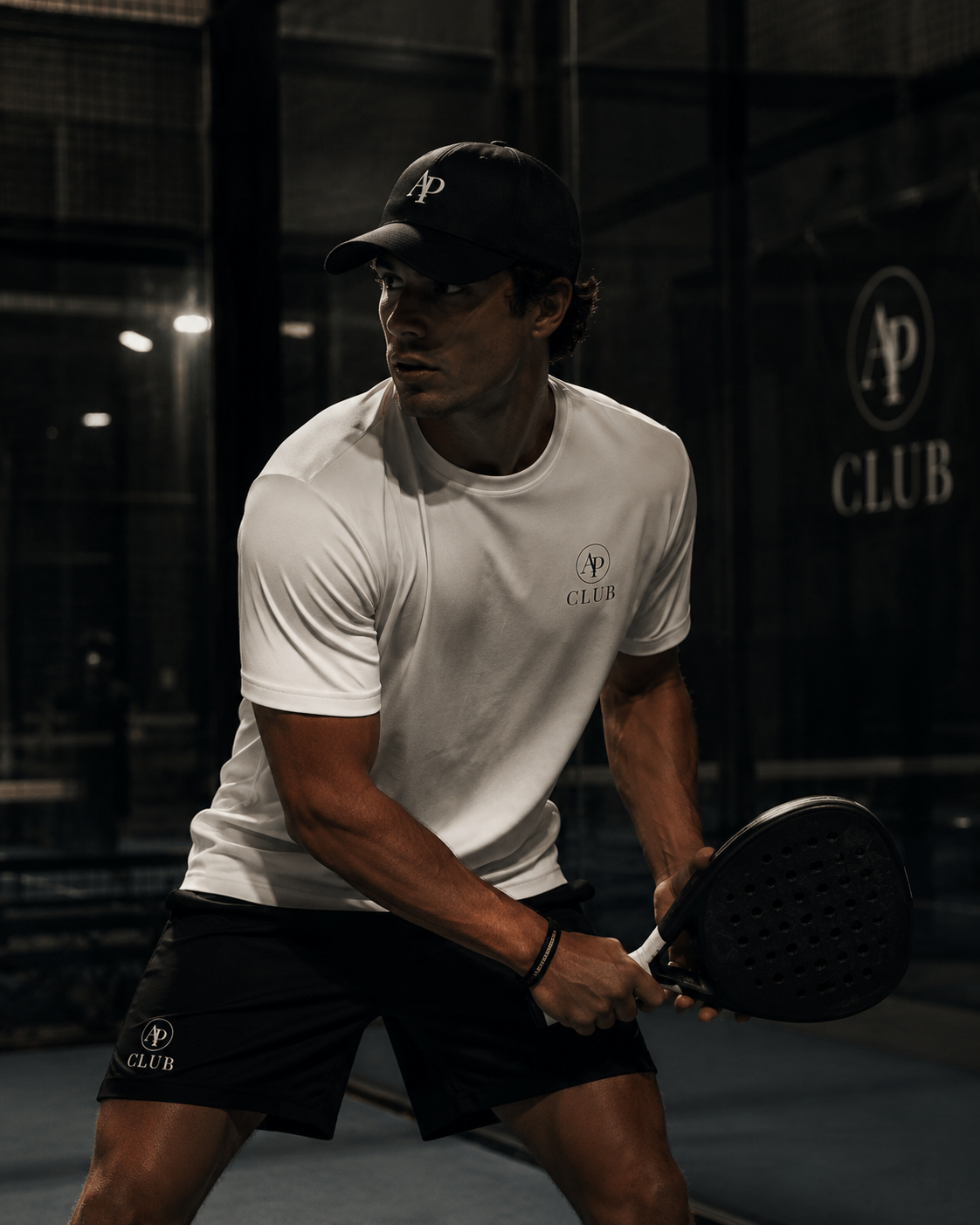 Person playing padel on a court wearing a white AP Club play tee.