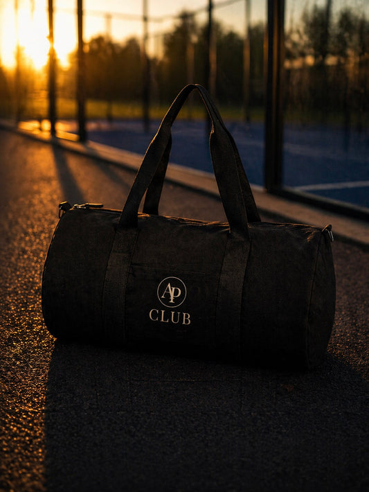 Black AP Club duffel bag with a logo on a padel court at sunset