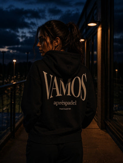 Female padel player wearing a black AP Club hoodie with 'VAMOS aprèspadel' text at night.